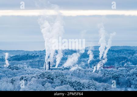 Steam rising from industry behind a forest Stock Photo