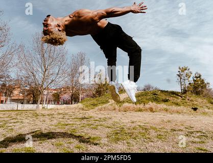 Stock photo of man doing somersault on field against clear sky Stock Photo