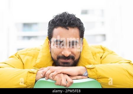 young man with yellow jacket and green chair Stock Photo