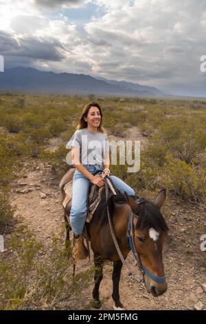 Woman smiling riding a horse in mountains of mendoza argentina Stock Photo