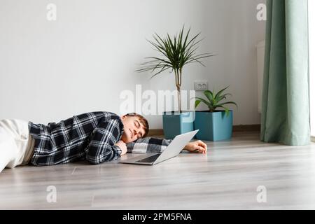 young man fell asleep on the floor in front of a laptop Stock Photo