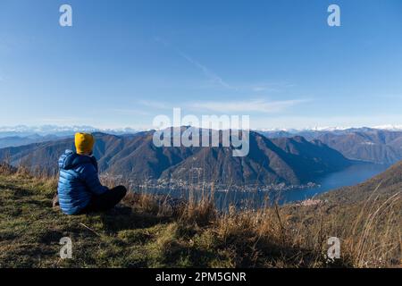 traveler man sitting on mountain top admiring landscape Stock Photo