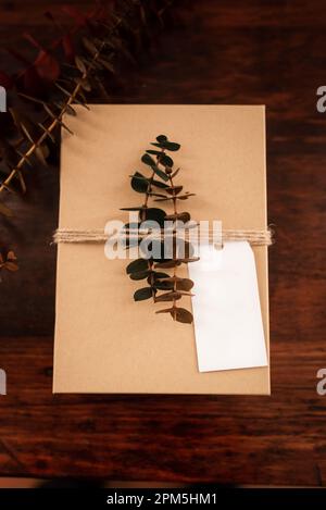 Blank white gift tag with brown present box, twine, eucalyptus leaves Stock Photo