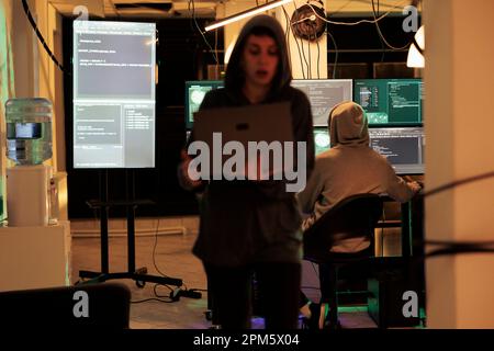 Hackers team using computers to plant virus and hack network system, trying to steal sensitive information from government server at night. Two spies hacking computer, identity theft. Stock Photo