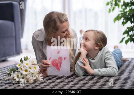 mother and daughter with card and flower bouquet Mother's Day, birthday or Women's Day at home  Stock Photo