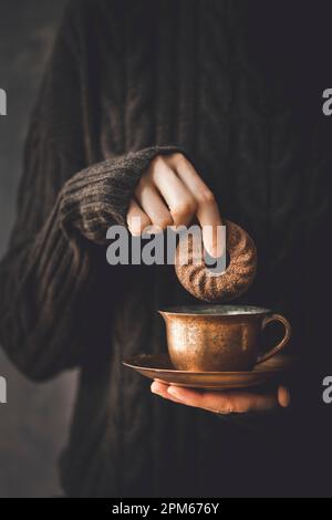 A Chocolate Donut being dipped in a hot coffee Stock Photo