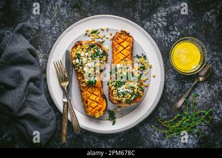Mustard Glazed Butternut Squash Halves Stuffed with Farro and Kale on Plate with glaze in bowl, Overhead Stock Photo