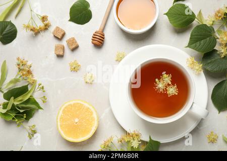 Flat lay composition with tasty tea and linden blossom on light grey marble table Stock Photo