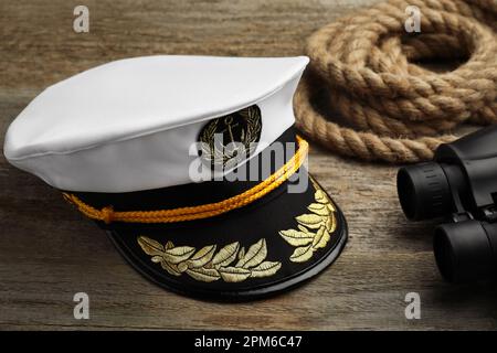 Peaked cap, rope and binoculars on wooden background Stock Photo