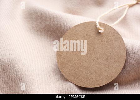 Circle shaped tag with space for text on beige fabric, closeup Stock Photo