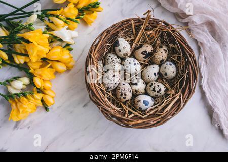 Quail eggs in a basket on white marble background Stock Photo