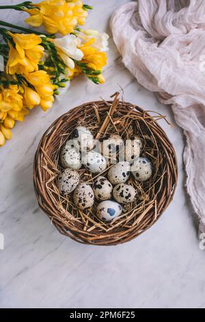 Quail eggs in a basket on white marble background Stock Photo
