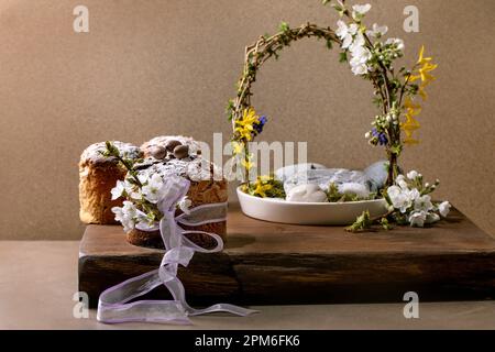 Homemade Italian traditional Easter panettone cakes, decorated by chocolate eggs, pink ribbon and blossoming cherry tree flowers standing on wooden ta Stock Photo