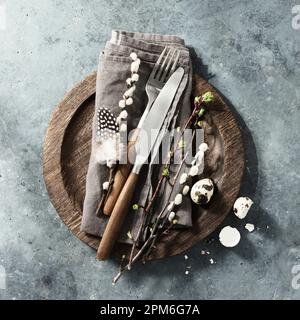 Easter table setting with spring flowers and cutlery on dark blue background top view flat lay. Happy Easter holiday concept for cafes and restaurants Stock Photo