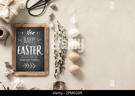 Easter composition with vintage Easter decorations and Happy Easter chalk board on beige stone background top view flat lay copy space Stock Photo