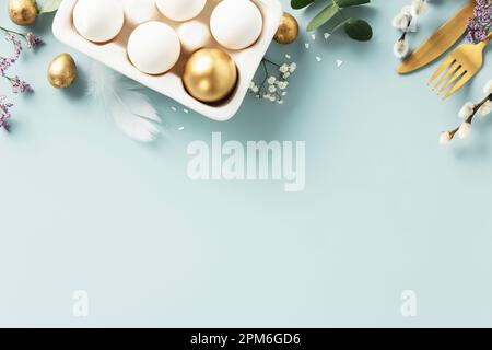 Easter table decorations. Happy Easter concept with golden table setting, easter eggs, feathers and spring flowers. Easter background with copy space. Stock Photo