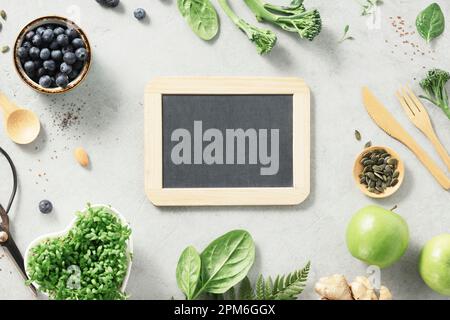 Vegetarian vegan healthy ingredients and empty chalk board on grey stone background. Healthy eating, eco friendly, zero waste concept Stock Photo