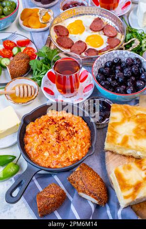 Turkish breakfast with menemen, eggs and sujuk, olives, jams, simit, borek, butter, honey, salad and Turkish tea. Stock Photo