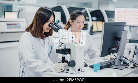 Team of medical research scientists collectively working on new research knowledge of sciences with microscope in laboratory. Medical technology. Stock Photo