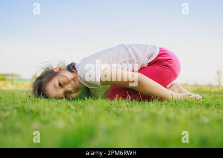 Little cute asian girl practicing yoga pose on a mat in park, Healthy and  exercise concept Stock Photo - Alamy