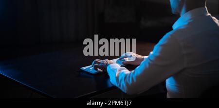 Rear view of a man typing on a keyboard in the dark.  Stock Photo