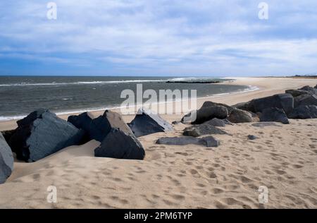Sandy beach with boulders on the Atlantic Ocean. Blue sky with wispy clouds on a winter's day, Sandy Hook Beach, New Jersey, USA, part of Gateway Nati Stock Photo