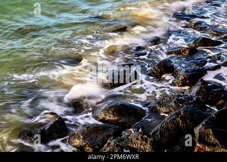 Waves splashing onto shoreline Rocks Stock Photo