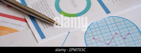 Metal pen on documents with colourful charts, graphs and diagrams Stock Photo