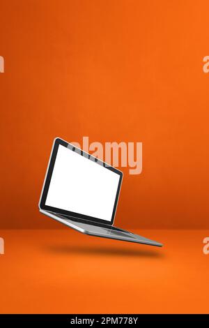 Blank computer laptop floating over an orange background. 3D isolated illustration. Vertical template Stock Photo