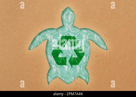 Sea turtle silhouette made of recycled paper with recycling symbol on plastic bubble wrap - Concept of ecology and ocean pollution Stock Photo