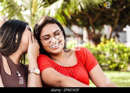 The two Hispanic smiling girls having a conversation in a park. Stock Photo