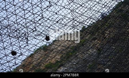 Falling rock stone rockfall slide protective fence barrier. Metallic net protects against falling rocks Stock Photo