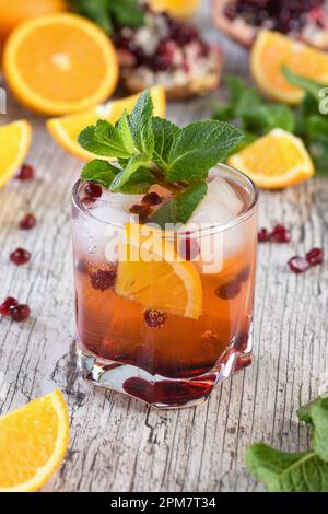 The cocktail is made from pomegranate and orange juice with tequila or gin, with the addition of tonic. Served in a glass with ice, orange slices with Stock Photo