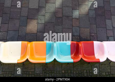 Bright multi-colored plastic seats against a gray sidewalk. View from above. Stock Photo
