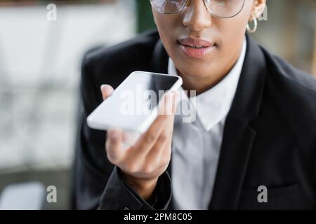 cropped view of african american businesswoman sending voice message on mobile phone in office,stock image Stock Photo