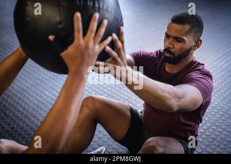 High angle view of biracial young male friends exercising with fitness ball while sitting in gym Stock Photo