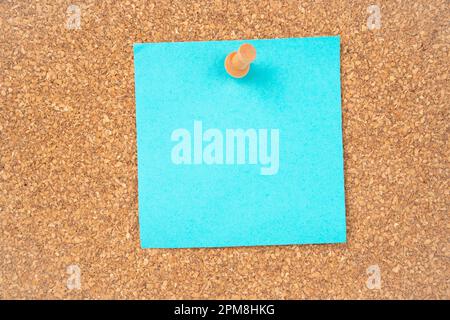 Blank blue sticky note paper and wooden thumbtack on wooden background. Stock Photo