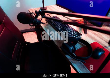 A modern computer desk featuring a laptop, keyboard, and headphones Stock Photo