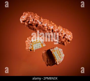 Crispy wafer coated chocolate bar suspended in the air with a brown gradient background. Stock Photo