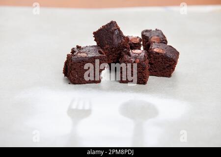 An image of four pieces of freshly-baked warm chocolate brownies, served on a plate with a fork Stock Photo