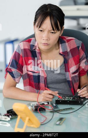 female technician using voltage meter on hard drive Stock Photo