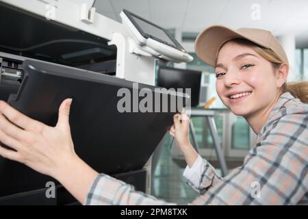 young woman fixing a printer Stock Photo