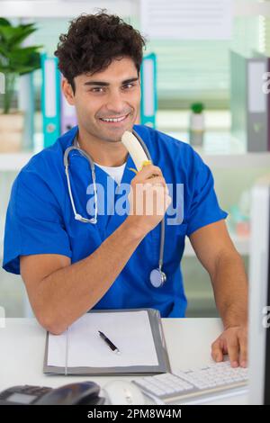 healthy doctor eating a banana at his office Stock Photo