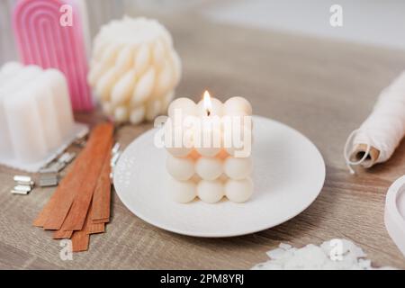 Burning beautiful white bauble candle on ceramic stand Stock Photo