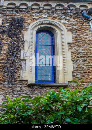 Vintage Window on a Stone Wall in the Old Style. An old Mansion Made of Orange Bricks. Ivy Grows on the Wall. Old Window Frames With White Stone Edges Stock Photo