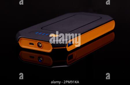 Battery power charger device isolated on a cool black reflective surface. Stock Photo