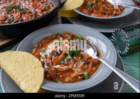 Tex mex bean stew with chicken and sour cream. Served with warm tacos Stock Photo