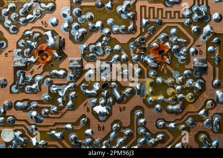 A part of a printed circuit computer board with tracks. PCB without radio components. Old printed circuit board background with soldering trace, close Stock Photo