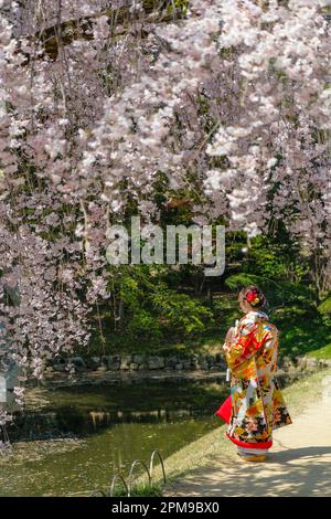 Okayama, Japan - April 4, 2023: A woman dressed in kimono in the Okayama Korakuen Garden, Korakuen is a Japanese garden located in Okayama, Japan. Stock Photo