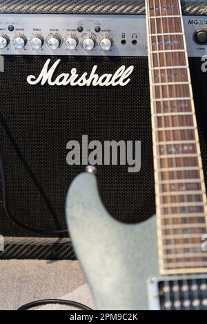 A classic Marshall guitar amp with a guitar leaning against it at home. Theme: adult hobbies, playing guitar, amp manufacturer, amplifier company Stock Photo